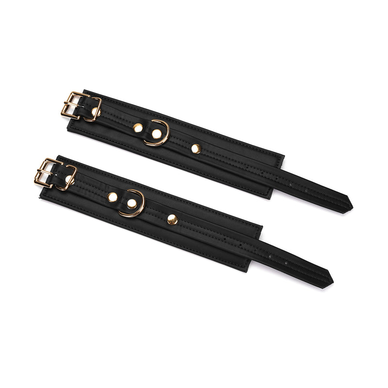 Black vegan leather handcuffs with gold hardware from Dark Candy collection, showcasing adjustable straps and D-rings for bondage play