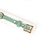 Close-up view of white and green leather BDSM collar with gold buckle and D-ring, part of Fairy collection
