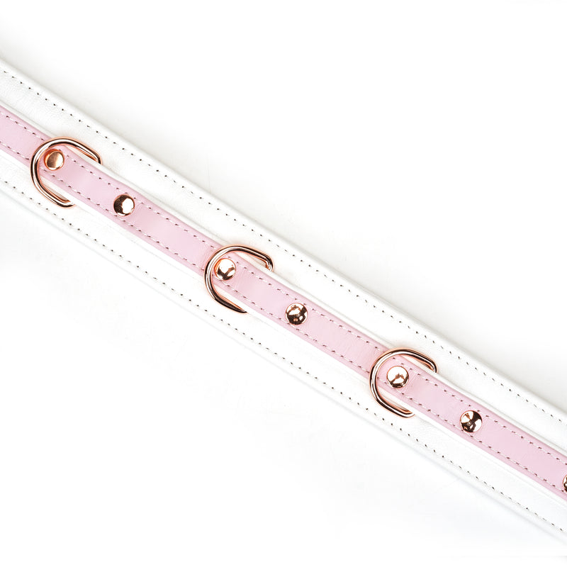 Close-up of a white and pink leather BDSM collar with rose gold accents from the Fairy collection, highlighting the premium build and adjustable features