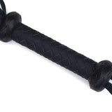 Close-up of vegan leather flogger handle with braided texture and end knots, designed for ethical bondage play