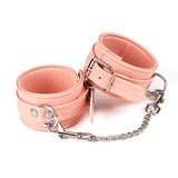 Pink vegan leather ankle cuffs with silver hardware and chain from the Dark Candy collection, ideal for BDSM play