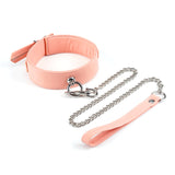 Pink vegan leather collar with chain leash from the Dark Candy collection, featuring adjustable buckle and D-ring for attaching bondage accessories