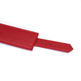 Close-up of adjustable faux leather red wrist cuff with multiple holes for customization, emphasizing passion and strength in bondage gear