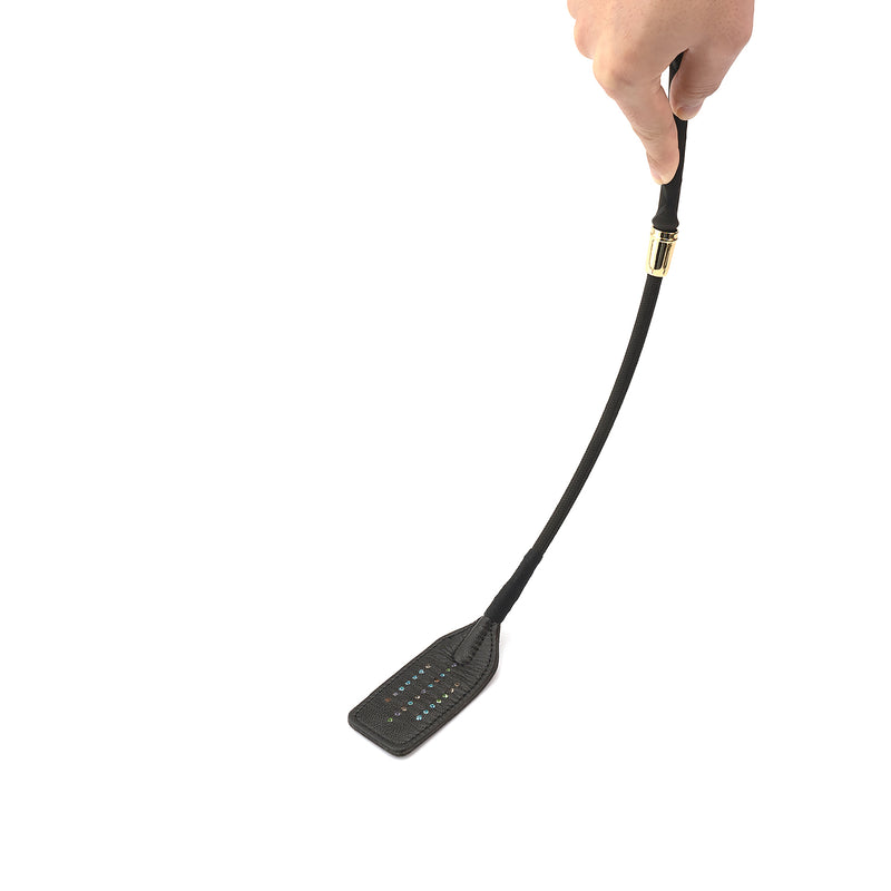 Hand holding a black leather Shining Girl Riding Crop with embedded gems, designed for elegant and stylish kinky play