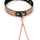 Rose gold leather bondage collar with attached nipple clamps and black closure details, set against a white background