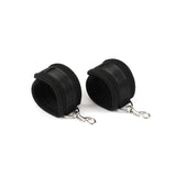 Black neoprene wrist restraints with Velcro fixtures and quick-release clips for beginner's bondage kit