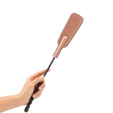 Hand holding a rose gold leather spanking crop with a textured corkscrew handle from the Rose Gold Memory collection