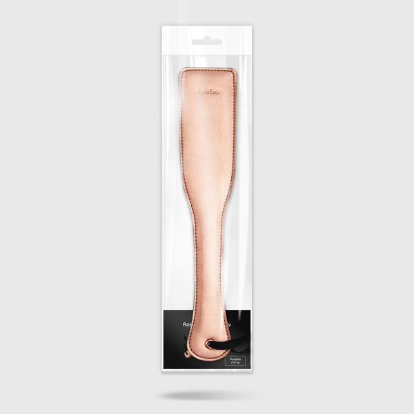 Rose Gold Memory leather spanking paddle in retail packaging, designed for indulgent impact play, featuring lightweight structure and wrist loop
