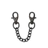 Black metallic swivel snap hooks connected by a chain, part of vegan leather wrist cuffs for BDSM play