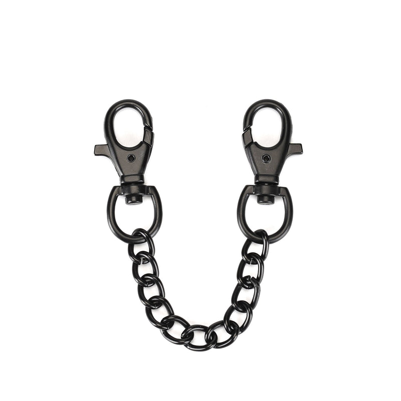 Black metallic swivel snap hooks connected by a chain, part of vegan leather wrist cuffs for BDSM play