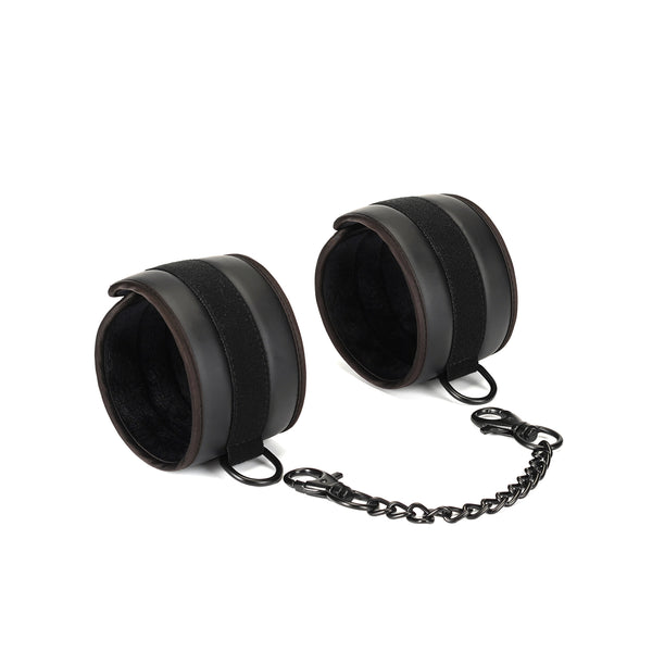 Vegan leather ankle cuffs with plush padding and connected by a Gothic black chain for ethical BDSM play