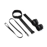 Vegan leather wrist-to-collar restraints set with padded collar, wrist cuffs, and leash for bondage play, displayed on a white background