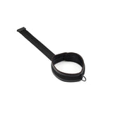 Vegan leather wrist-to-collar restraint with metal D-ring and padded black wrist cuffs, ideal for bondage play