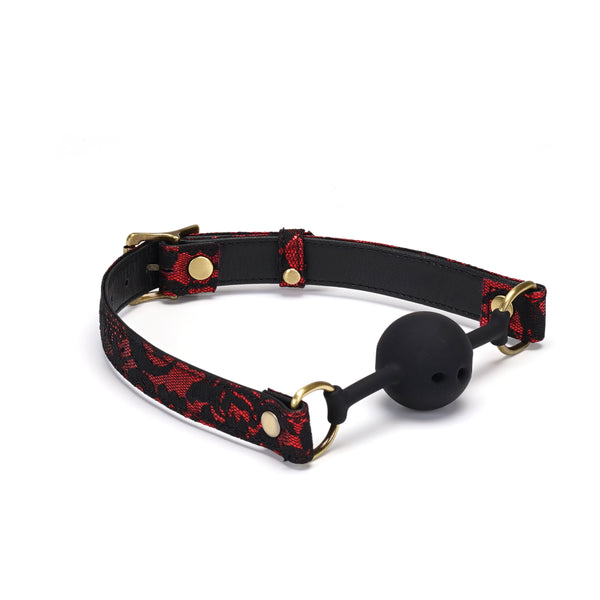 Victorian-style breathable silicone ball gag featuring red lace design on vegan leather straps with golden metal hardware for BDSM play