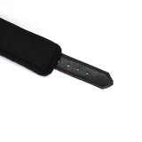 Close-up of adjustable black vegan leather bondage strap with plush lining for BDSM play, showing detail of adjustment holes and stitch work