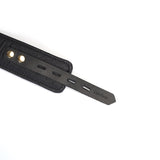 Close-up of luxury black leather handcuff strap with gold hardware and multiple adjustment holes, part of BDSM bondage accessories