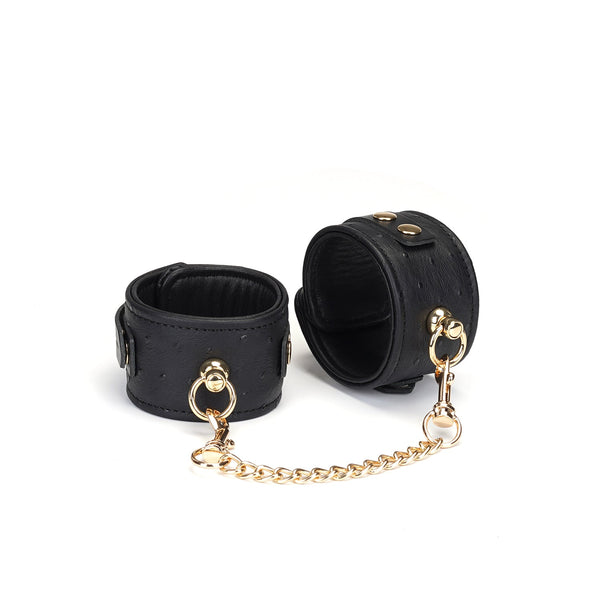 Luxurious black leather ankle cuffs with ostrich skin pattern and gold hardware from Demon's Kiss collection, ideal for BDSM play