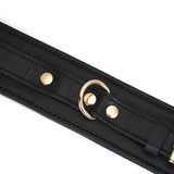 Black leather bondage ankle cuffs with gold buckle and rivets, compatible with bondage accessories