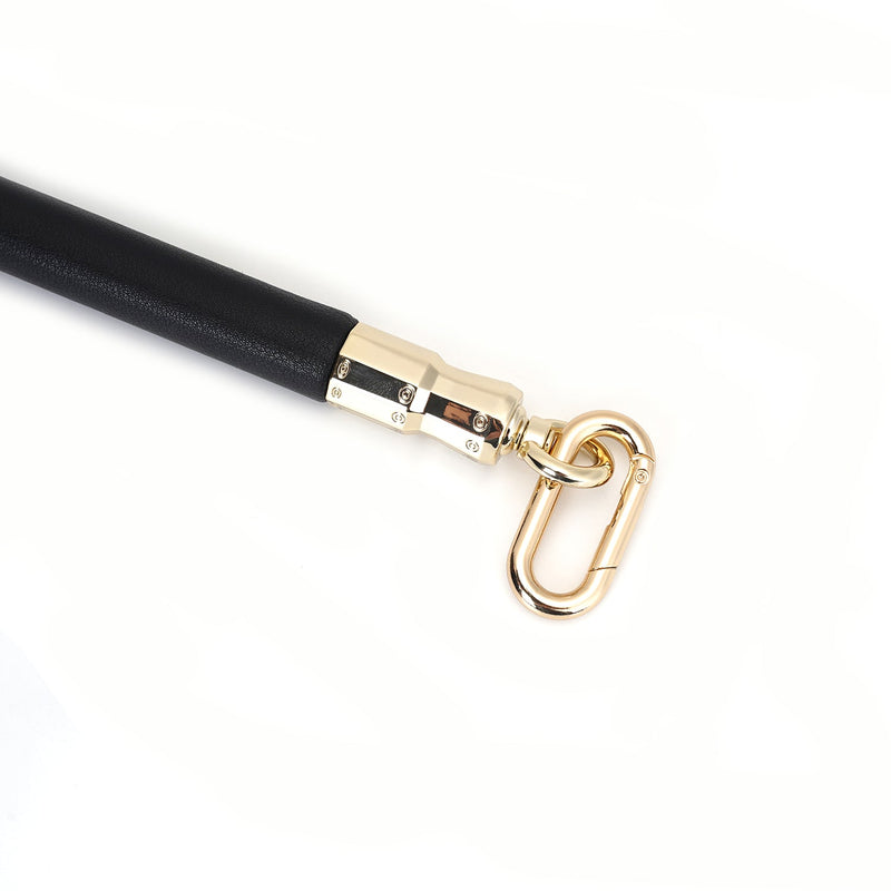 Close-up of black leather-coated leg spreader bar with gold metal quick-release clip, part of Dark Secret bondage collection