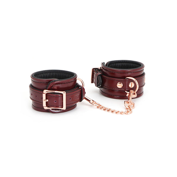 Wine red leather handcuffs with rose gold hardware on a white background, adjustable high-quality leather bondage wrist restraints from LIEBE SEELE