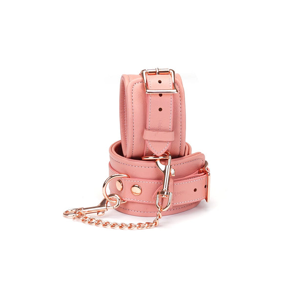 Pink Dream leather handcuffs with rose gold hardware, featuring glossy studs and adjustable straps