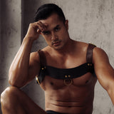 Man modeling luxury dark brown leather chest harness from The Equestrian collection by LIEBE SEELE, featuring quilted detailing and golden metal accents