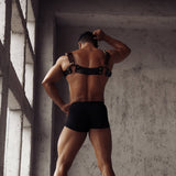 Muscular man modeling The Equestrian leather chest harness with vintage gold buckles, embodying high-end BDSM fantasy