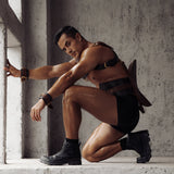 Man showcasing The Equestrian leather saddle harness for BDSM pony play in a rugged setting, featuring quilted detailing and adjustable straps