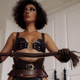 Confident woman dressed in leather harness and holding a leather cat o' nine tails flogger from The Equestrian collection
