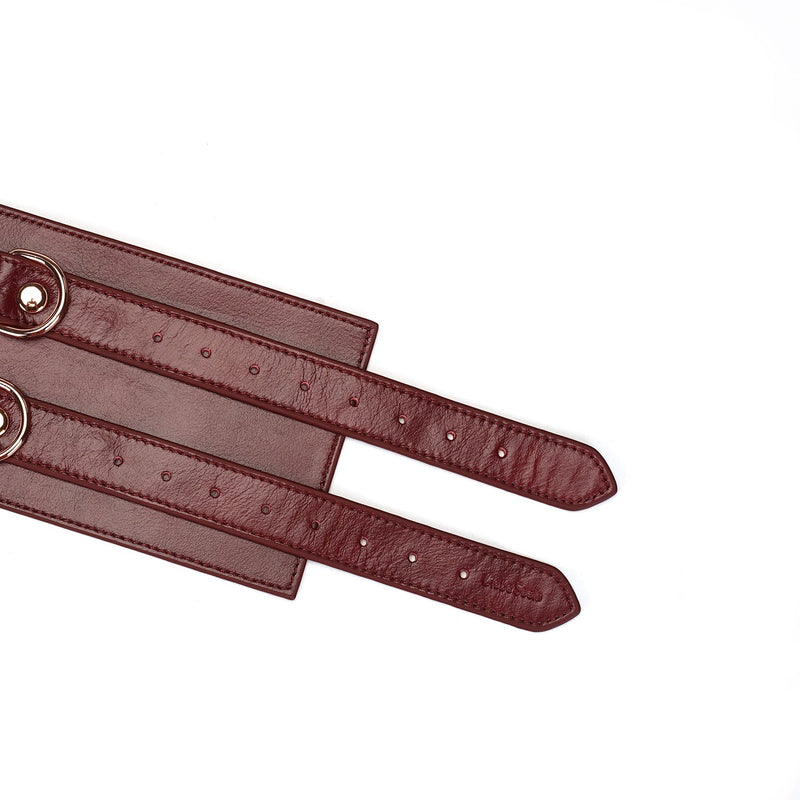 Wine red leather bondage waist belt detailed with rose gold buckles and adjustable strap holes, part of the Wine Red fetishwear collection