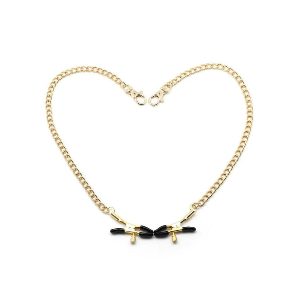 Gold metal chain and bull nose nipple clamps with adjustable black rubber tips for restraint play, displayed in a heart shape