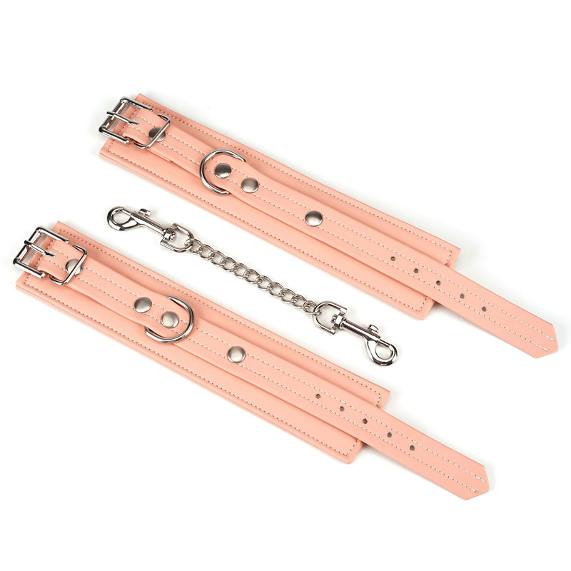 Pink vegan leather handcuffs with silver hardware and connecting chain for BDSM play, part of the Dark Candy collection