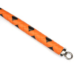 Close-up view of a hand-crafted, two-tone orange and black leather whip with a metal ring, designed for precision use in professional dominatrix sessions