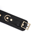Black leather bondage wrist cuff with golden buckle and D-ring, part of the Dark Secret collection