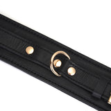 Close-up of a black leather bondage wrist cuff with golden buckles and rivets, part of the Dark Secret collection