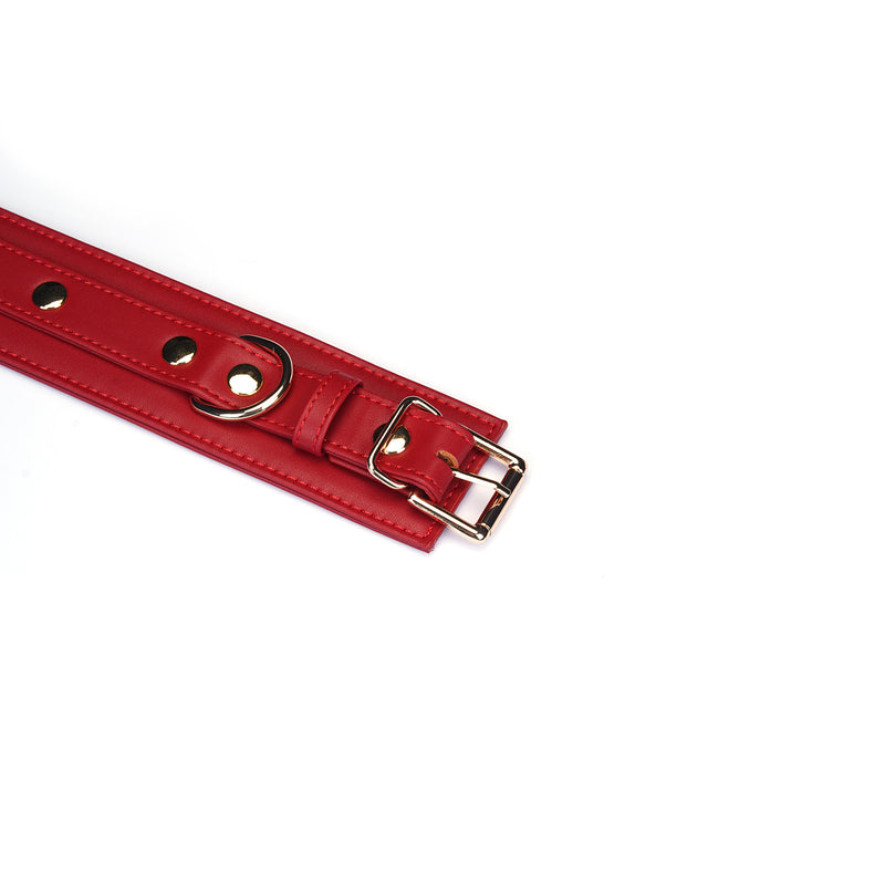 Red faux leather wrist cuff with metallic buckle, adjustable for erotic bondage play