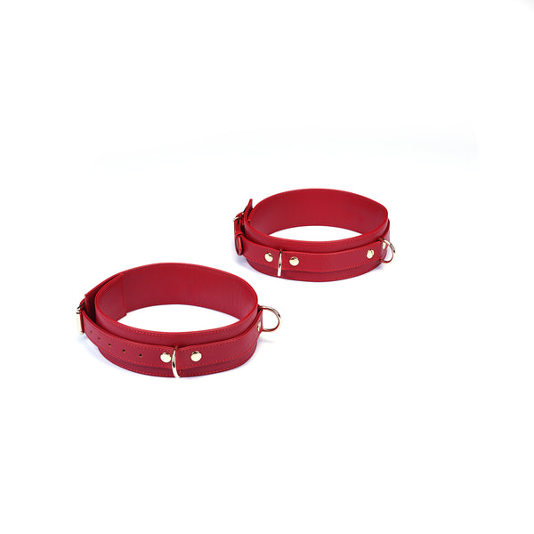 Red faux leather wrist to thigh cuffs kit with adjustable buckles and gold-tone hardware for BDSM play
