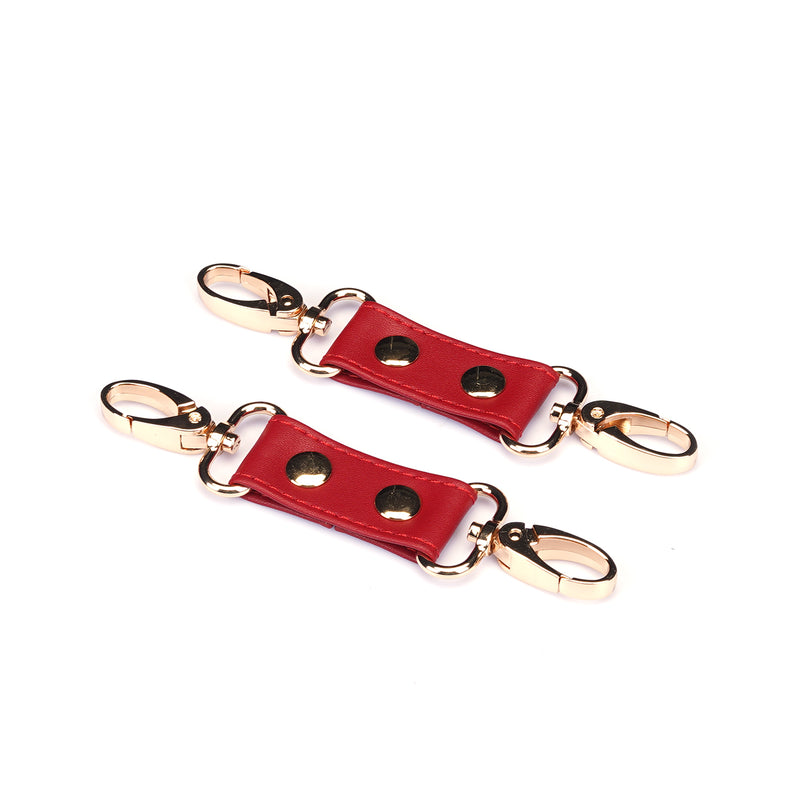 Red faux leather wrist to thigh cuff connectors with golden clasps for bondage play