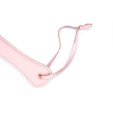 Premium pink leather spanking paddle with wrist strap and rose gold accents from the Fairy collection, ideal for bondage play