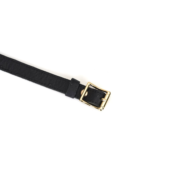 Close-up view of the Demon's Kiss black leather 'Slut' choker with ostrich skin pattern and gold buckle, displaying luxury BDSM accessory