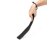 Hand holding black leather spanking paddle with ostrich skin pattern from Demon's Kiss collection for bondage play