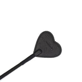 Black leather riding crop with heart-shaped tip and ostrich skin texture for BDSM play