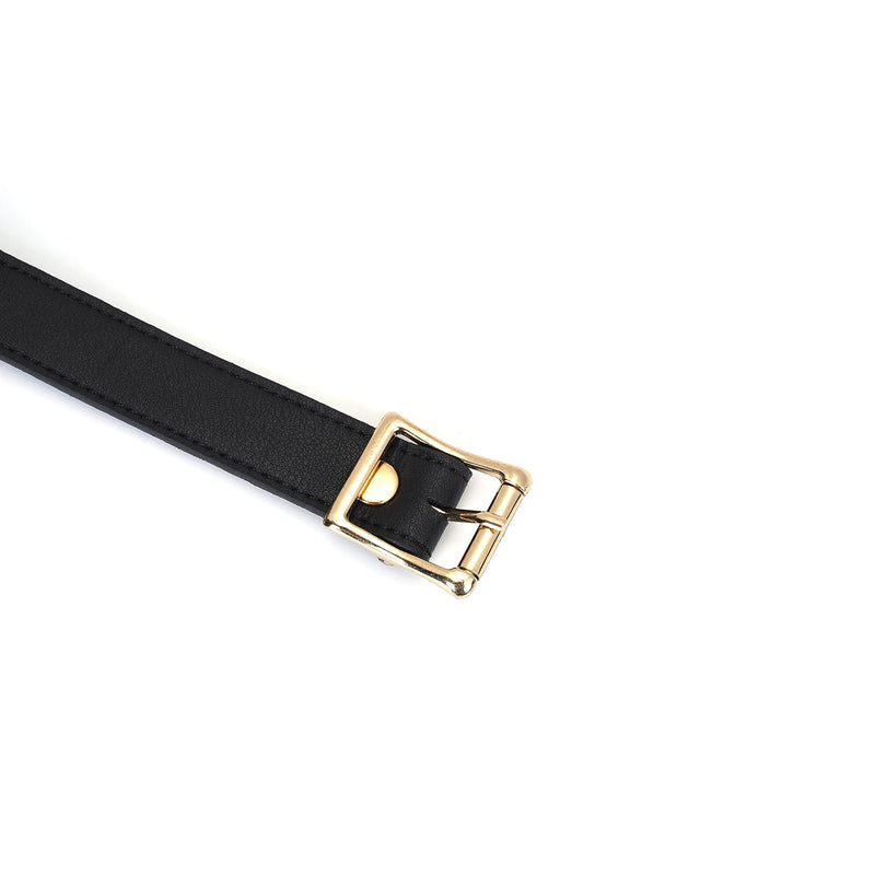 Close-up view of a black leather bondage gag strap with a gold-toned buckle, part of the Dark Secret collection