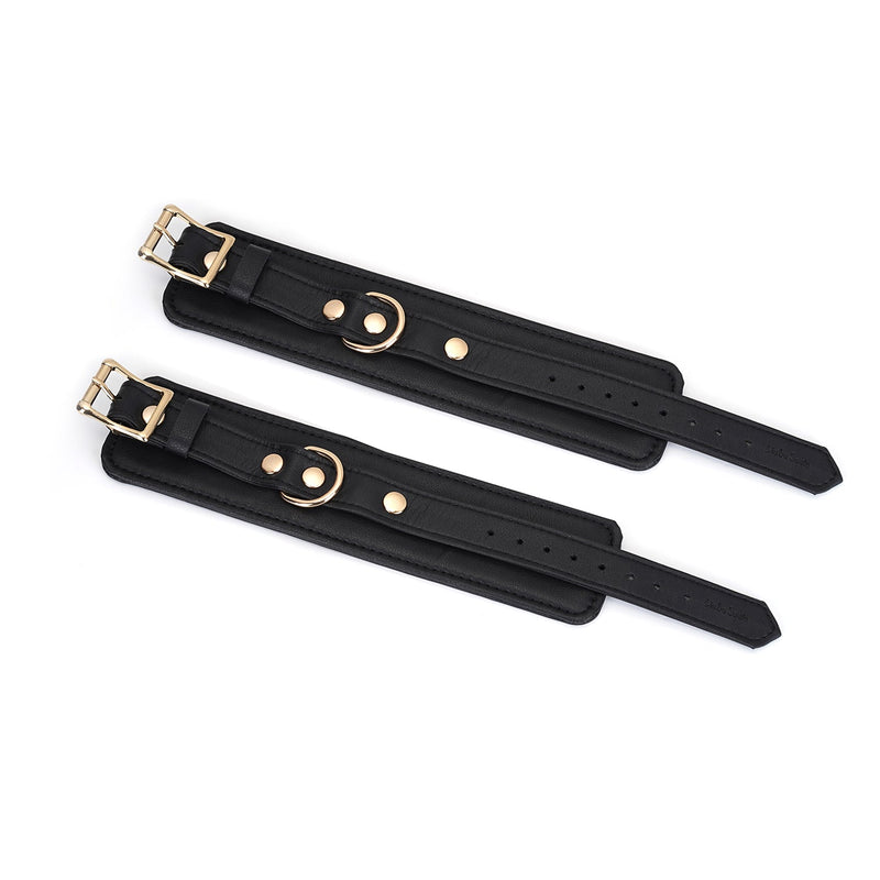 Black leather bondage wrist cuffs with gold hardware, adjustable for luxury restraint play