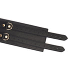 Close-up of black leather bondage belt with gold buckles, part of Dark Secret BDSM fetish wear collection