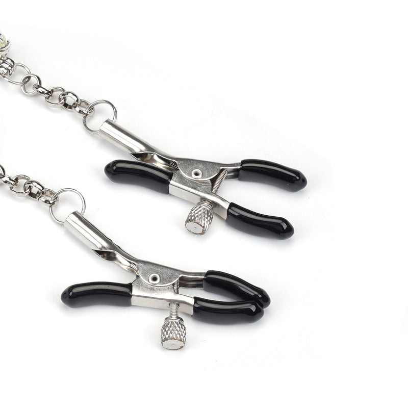 Adjustable nipple clamps with heart-shaped glowing stones and rubber tips for comfort, connected by a silver chain